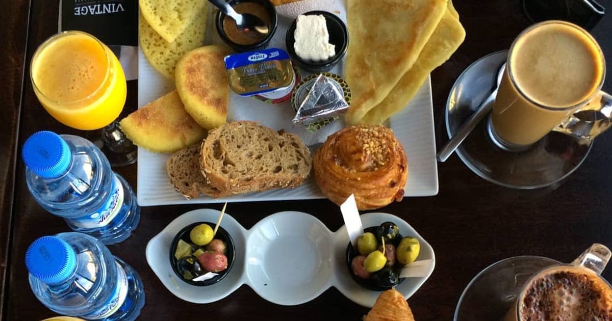 Petit-déjeuner servi au Vintage : msemen, baghrir, pain, viennoiserie, olives, jus d’orange et café au lait, vus de dessus