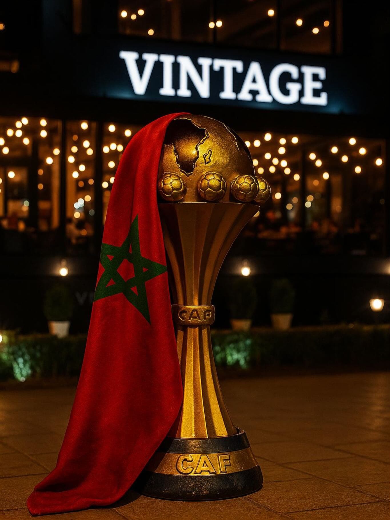 Le trophée et le drapeau du Maroc devant l’enseigne Vintage, le soir